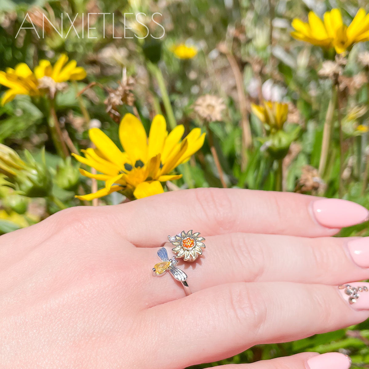 Woman wearing a sunflower and bee anxiety ring in silver that spins on yellow flower background