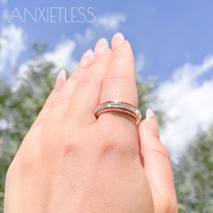Rose Gold crystal fidget ring worn on index finger, with trees and sky in the background