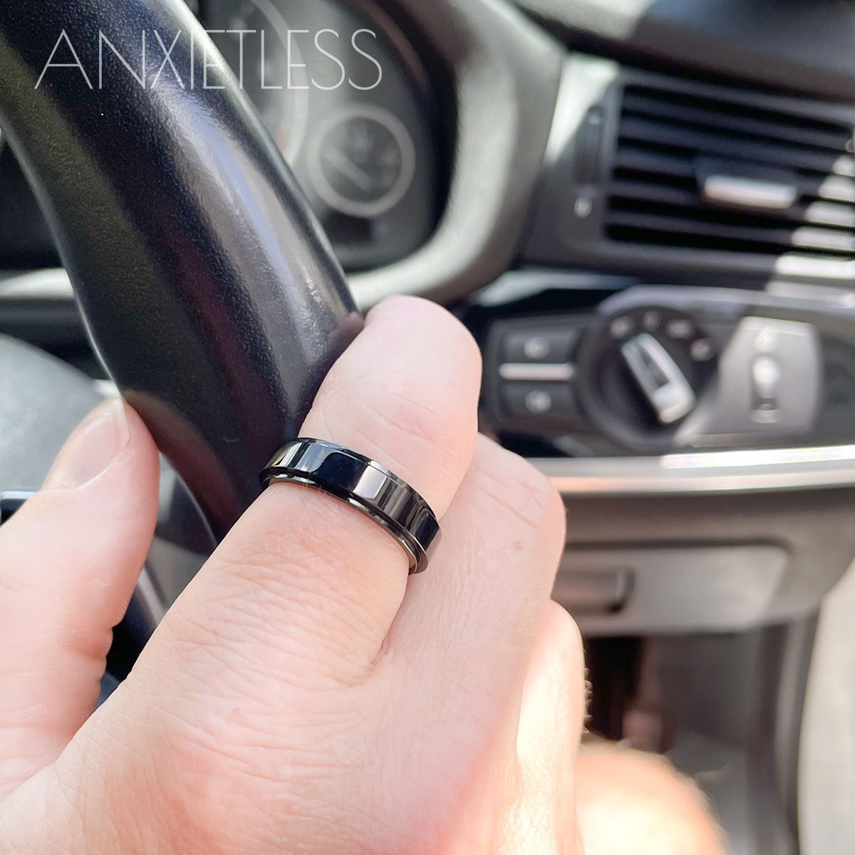 Man wearing a black fidget ring with a smooth polished design, holding onto a car steering wheel